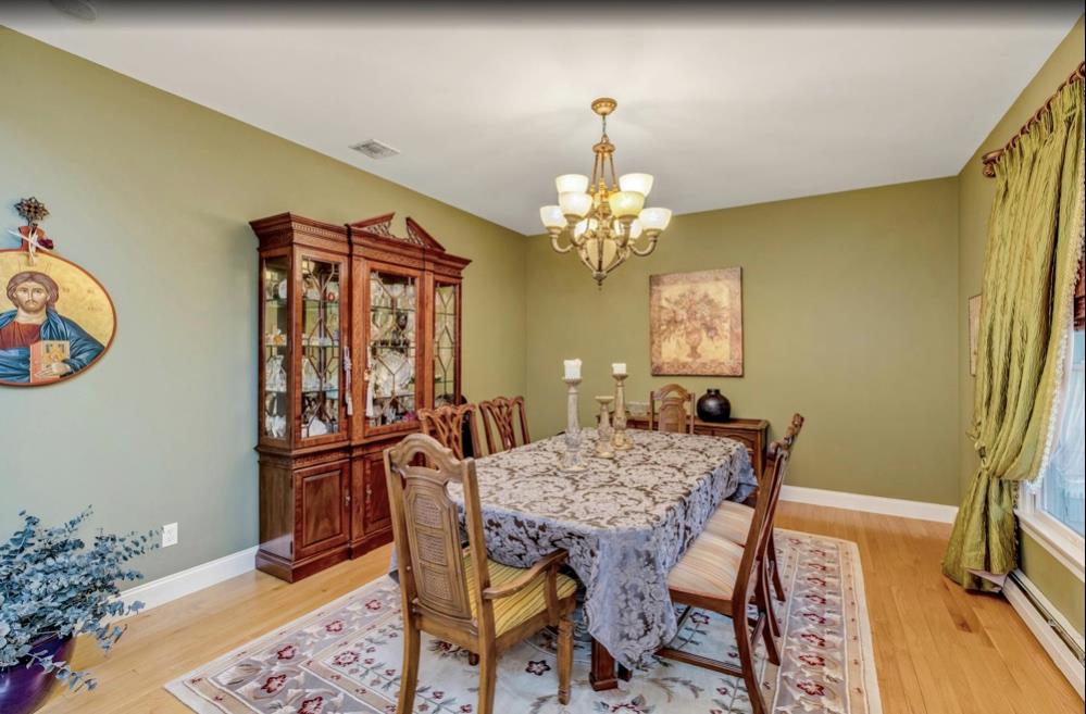 2655 Rocky Point Road East Marion, NY 11939 - Photo 6 of 23 Dining area featuring an inviting chandelier, light wood-style floors, baseboards, and baseboard heating