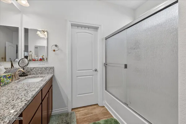 a bathroom with a granite countertop sink a mirror and shower