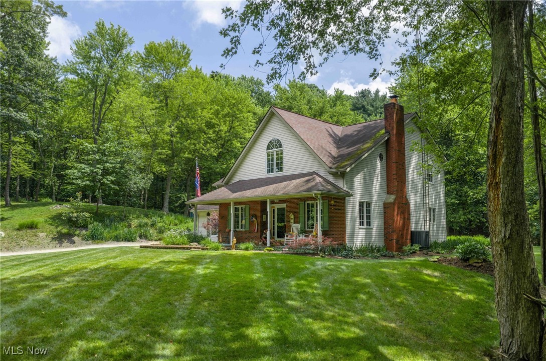 6535 Middle Run Road Dover, OH 44622 - Photo 39 of 40 View of front facade featuring a porch, a front lawn, brick siding, and a chimney