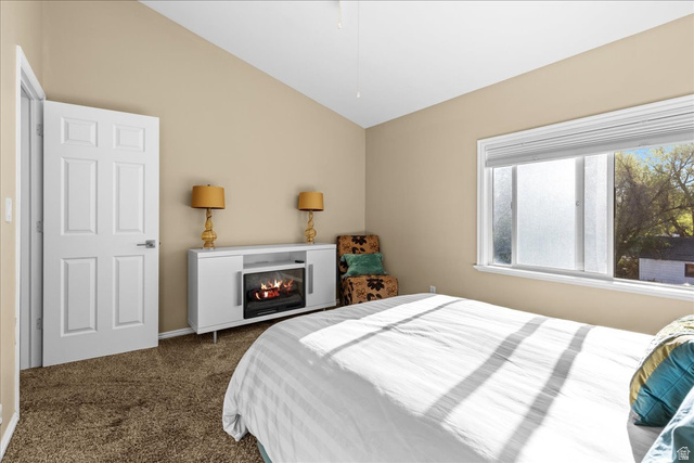 7824 South Sequoia Tree Lane Sandy, UT 84094 - Photo 27 of 43 Bedroom with lofted ceiling, dark colored carpet, and a glass covered fireplace