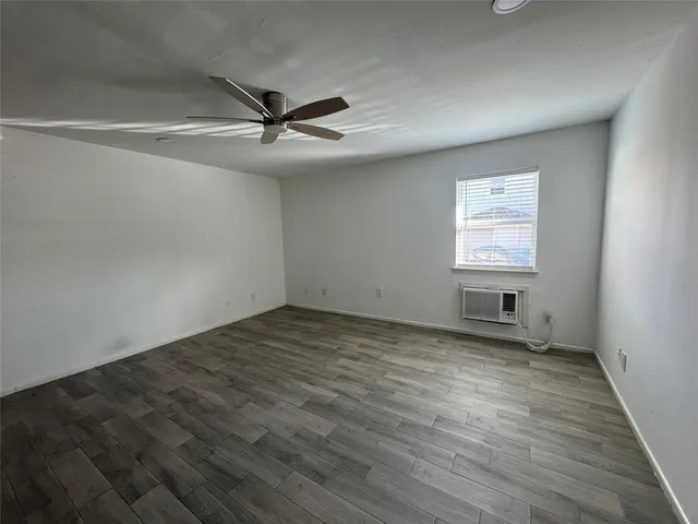 an empty room with wooden floor ceiling fan and windows