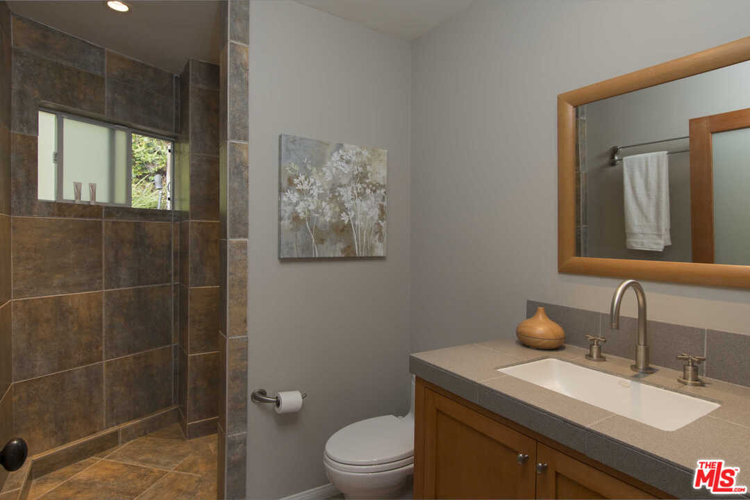 8027 Briar Summit Drive Los Angeles, CA 90046 - Photo 40 of 43 a bathroom with a granite countertop toilet a sink and mirror