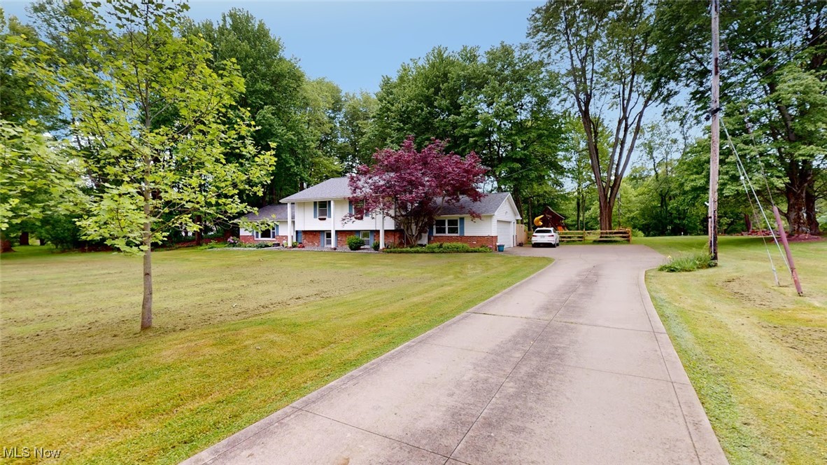 View of front of house featuring cement driveway, a front lawn and an attached garage