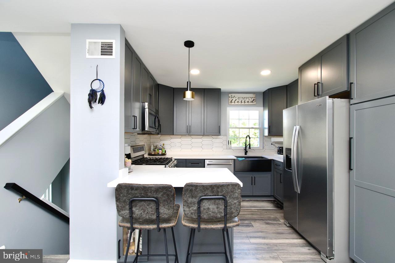 22908 Regent Terrace Sterling, VA 20166 - Photo 14 of 31 a kitchen with stainless steel appliances kitchen island granite countertop a refrigerator a sink a stove and chairs with wooden floor