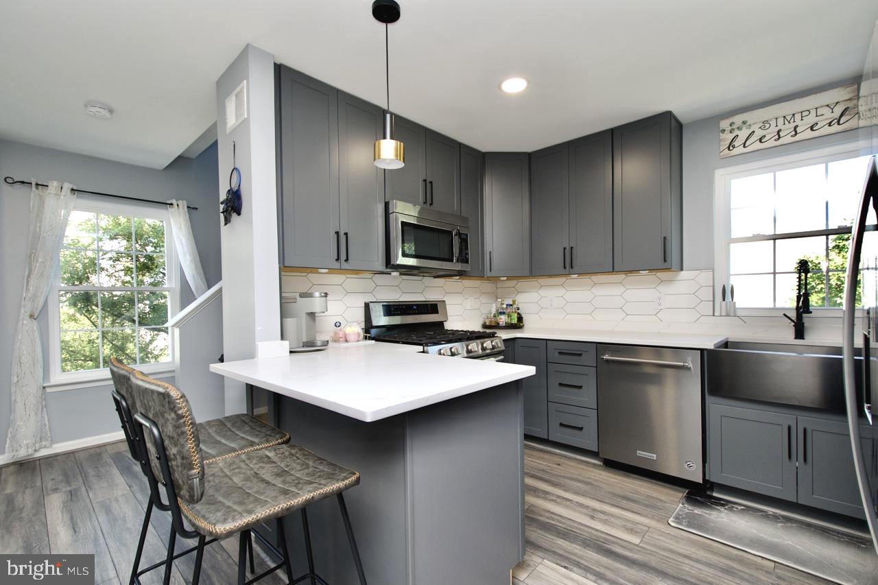 22908 Regent Terrace Sterling, VA 20166 - Photo 6 of 31 a kitchen with a stove a sink a dining table and chairs