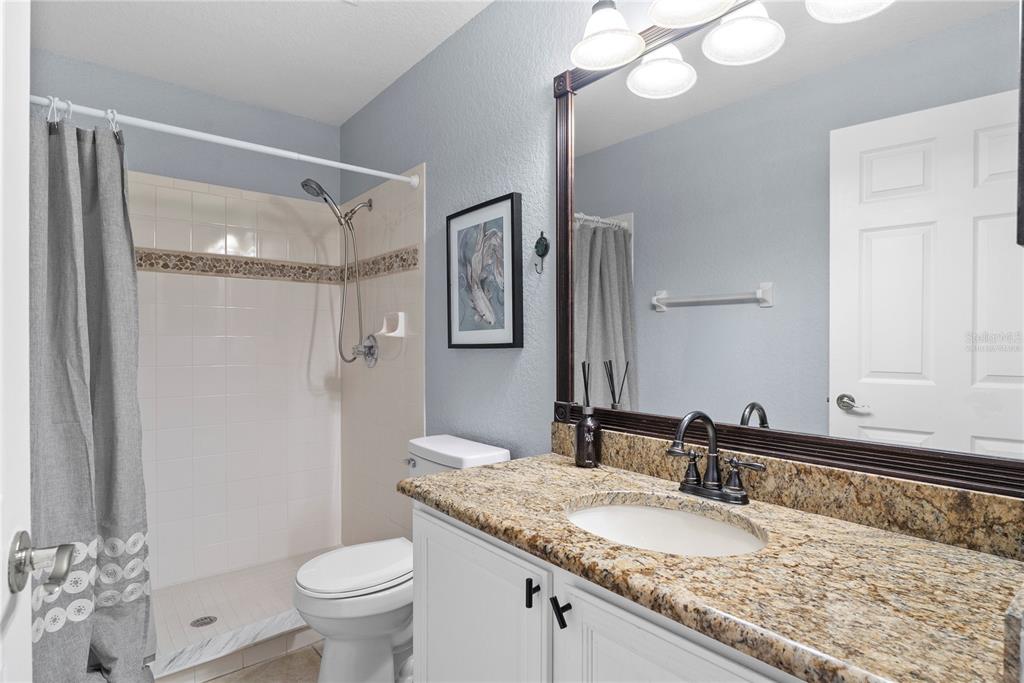 2264 Stone Cross Circle Orlando, FL 32828 - Photo 16 of 45 a bathroom with a granite countertop sink toilet mirror and a shower