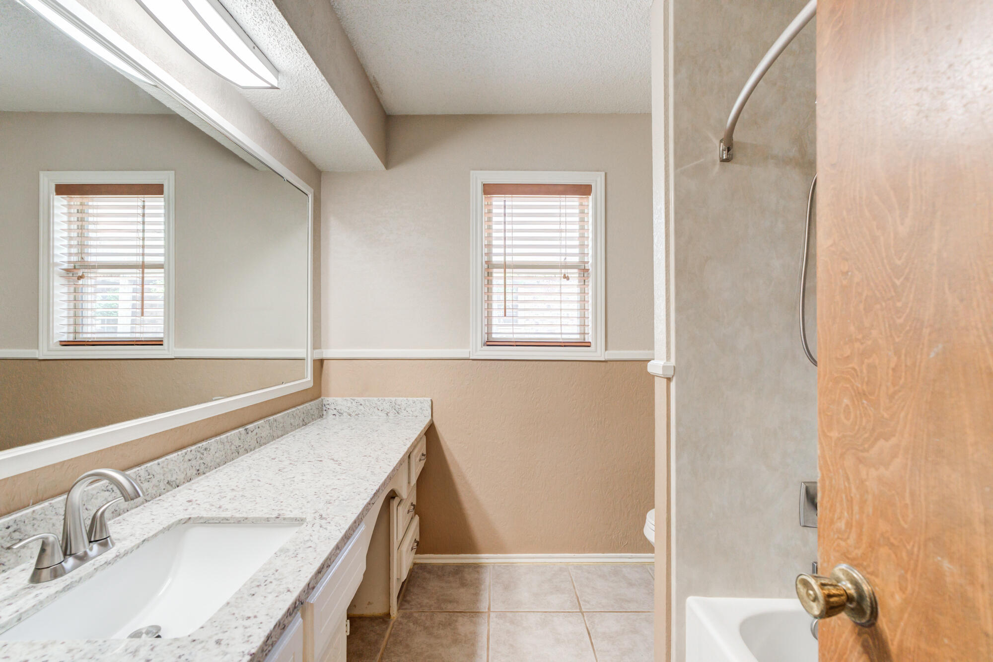 26 Highland Drive Ransom Canyon, TX 79366 - Photo 37 of 53 a bathroom with a granite countertop sink a mirror and a shower