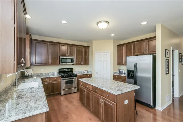 a kitchen with stainless steel appliances granite countertop a stove top oven a refrigerator and a sink