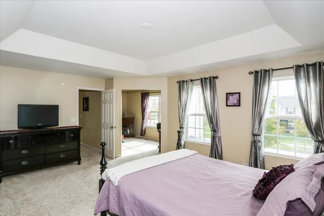 a bedroom with a bed and a flat tv screen on dresser