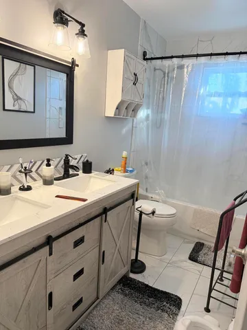 a bathroom with a double vanity sink toilet and shower
