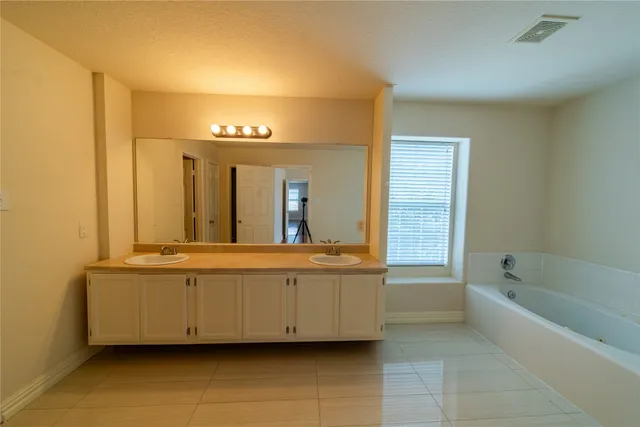 a spacious bathroom with a tub sink and mirror