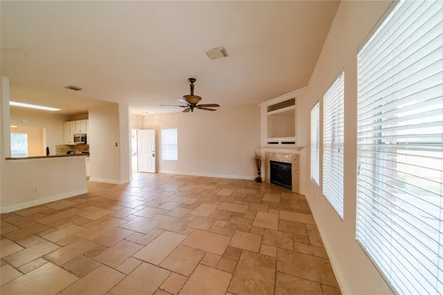 a view of a livingroom with a fireplace a ceiling fan and windows