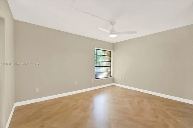 an empty room with windows and ceiling fan