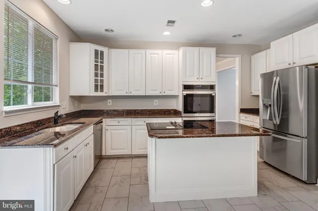 a kitchen with stainless steel appliances granite countertop a stove a sink and a refrigerator