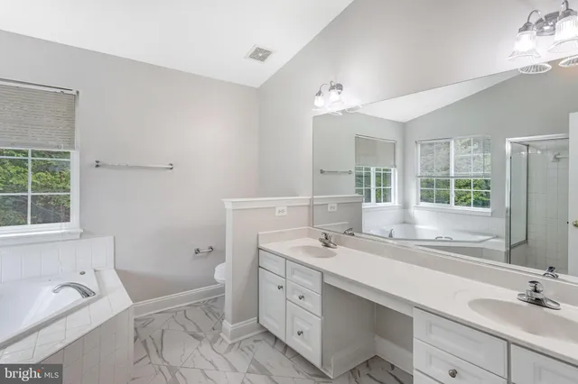 a spacious bathroom with a double vanity sink a mirror and a bathtub