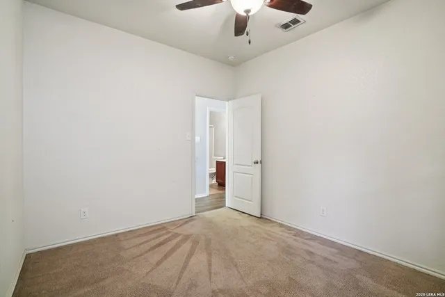 an empty room with a ceiling fan and carpet
