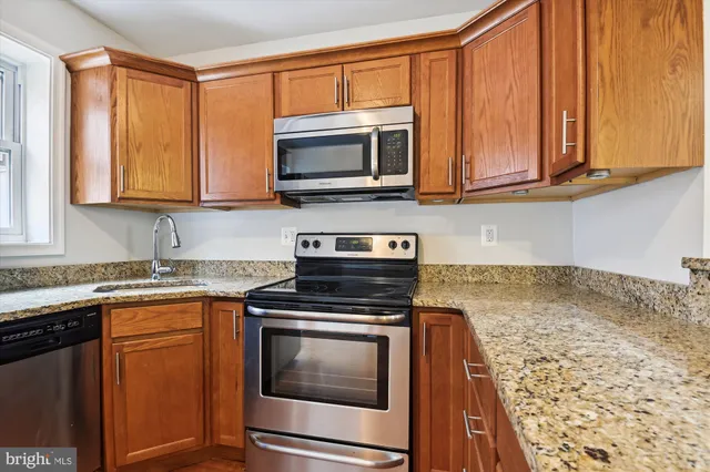 a kitchen with granite countertop a refrigerator stove and microwave