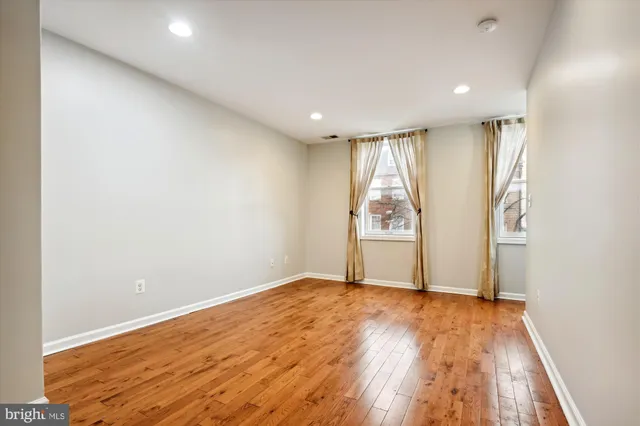 a view of an empty room with wooden floor and windows