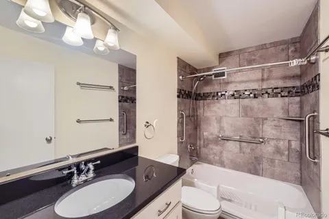 a bathroom with a sink vanity granite toilet tub and shower