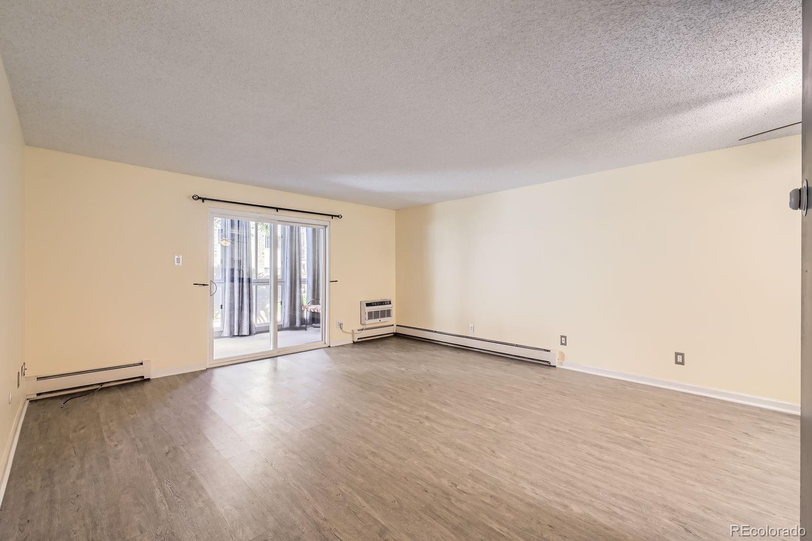 3124 South Wheeling Way, Unit 102 Aurora, CO 80014 - Photo 7 of 17 an empty room with wooden floor and windows