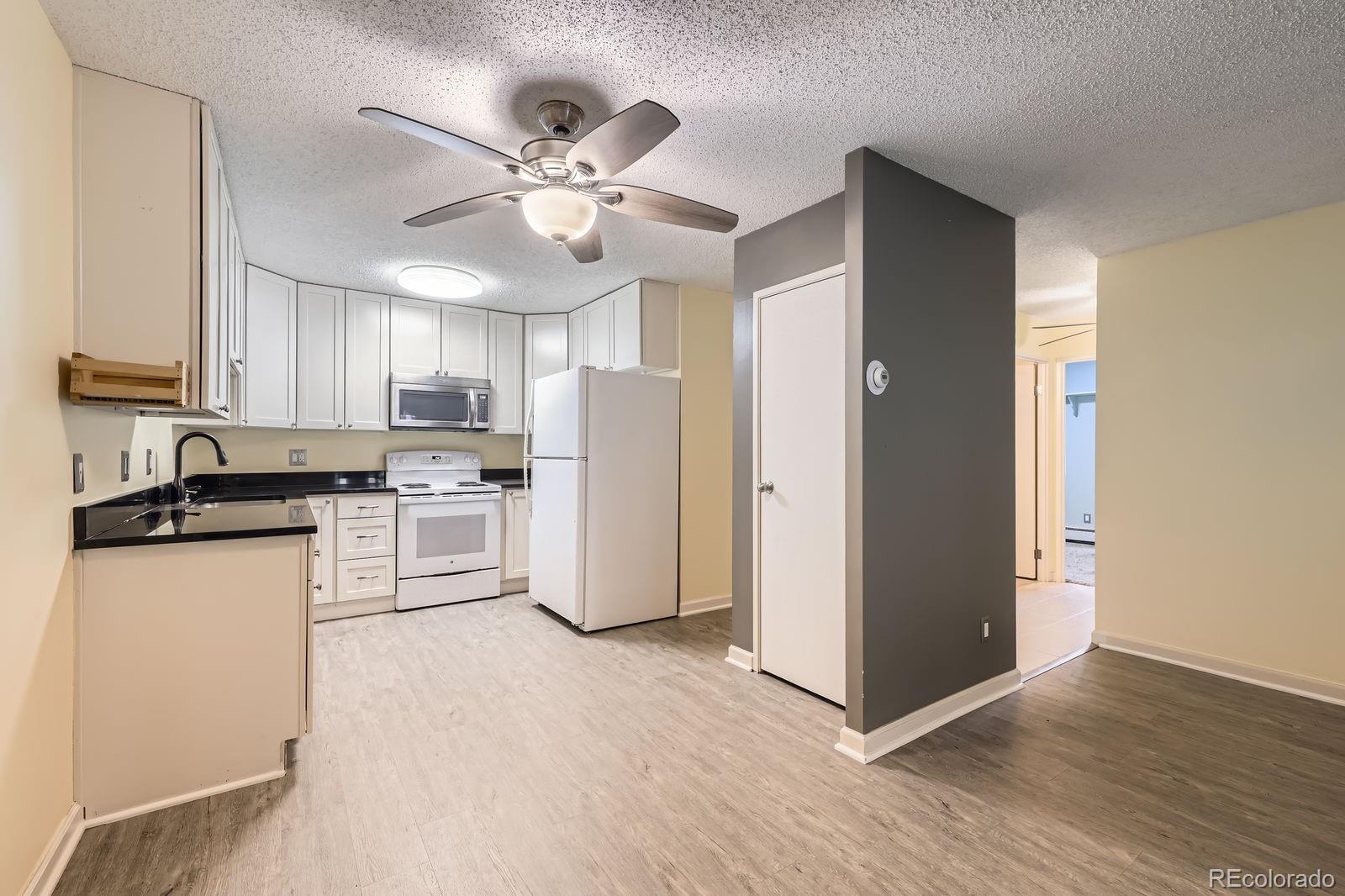 3124 South Wheeling Way, Unit 102 Aurora, CO 80014 - Photo 9 of 17 a kitchen with white cabinets and stainless steel appliances