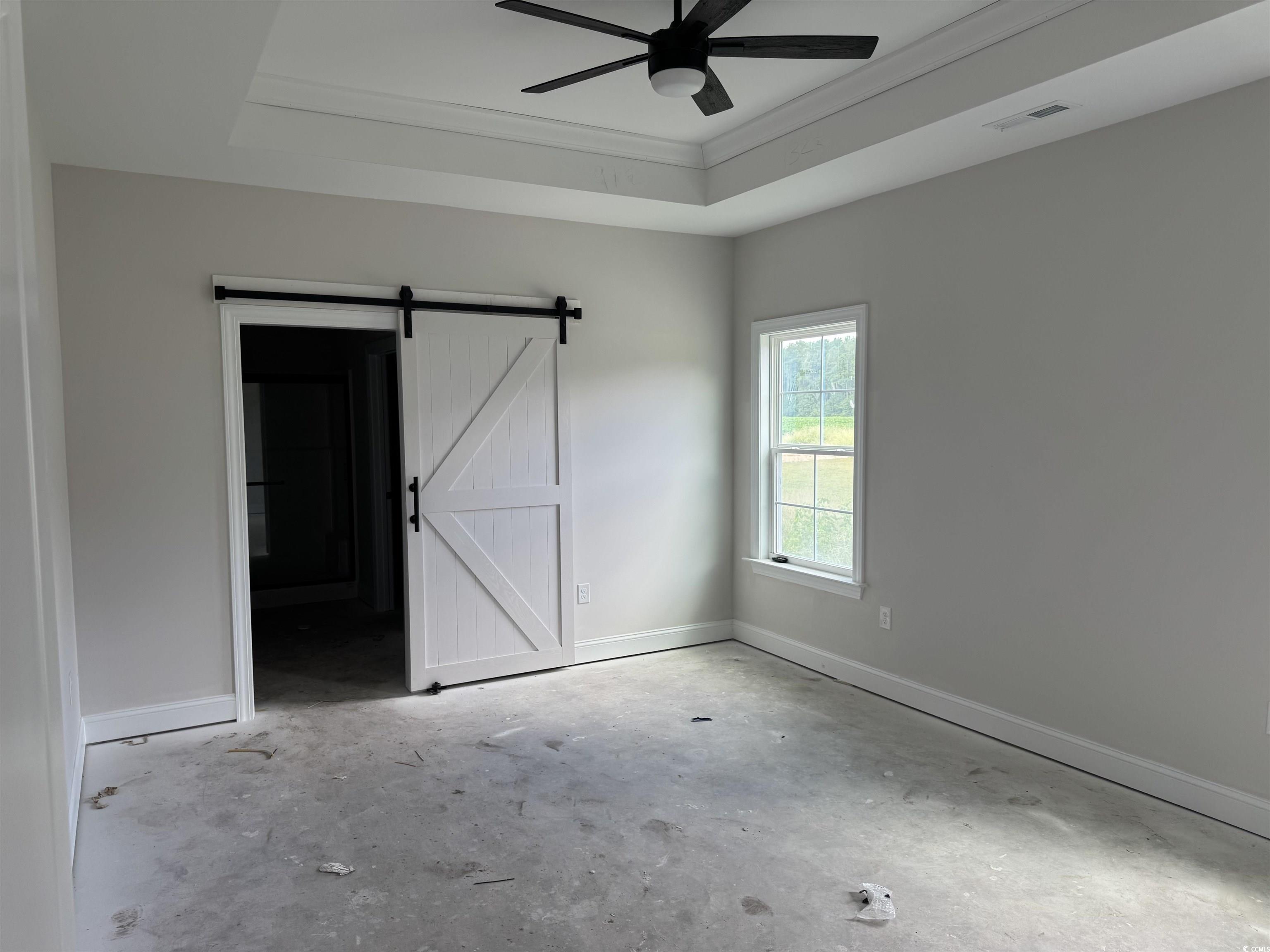4971 Dupont Road Aynor, SC 29511 - Photo 7 of 12 Unfurnished bedroom with a barn door, unfinished concrete floors, a raised ceiling, and ornamental molding