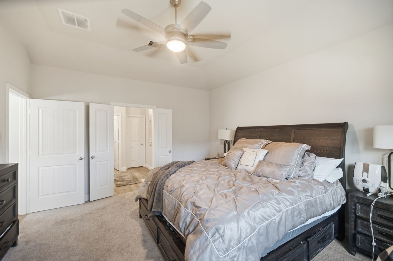 15326 Leal Rancho Court Cypress, TX 77433 - Photo 19 of 31 a bedroom with a bed and a chandelier