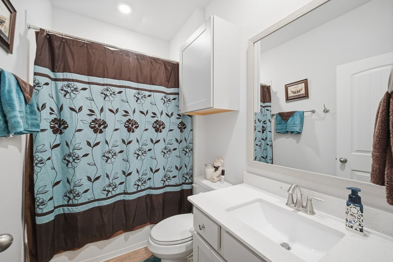 15326 Leal Rancho Court Cypress, TX 77433 - Photo 26 of 31 a bathroom with a sink a toilet and shower curtain
