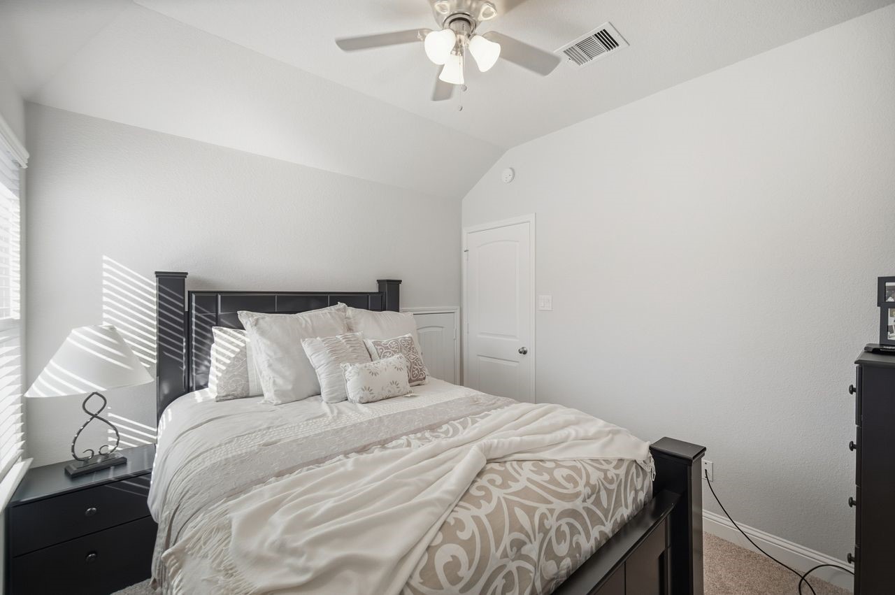 15326 Leal Rancho Court Cypress, TX 77433 - Photo 29 of 31 a bedroom with a bed and a chandelier
