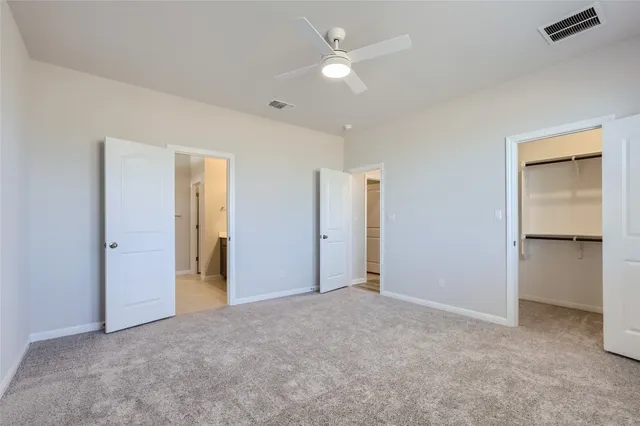 an empty room with closet and a ceiling fan