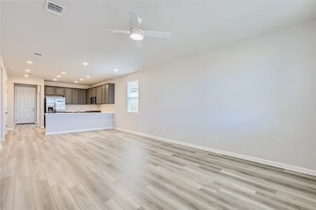a view of kitchen and empty room with wooden floor