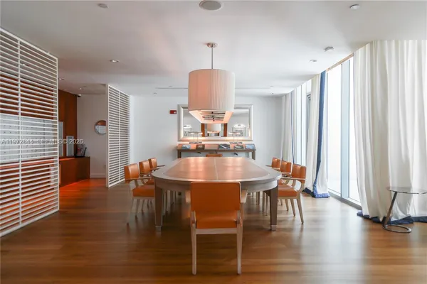 a dining room with furniture wooden floor a rug a fireplace and a chandelier