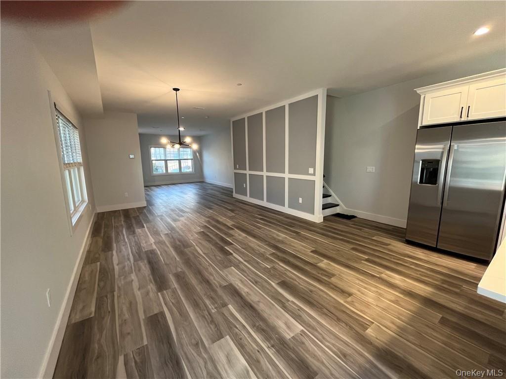 195 Park Avenue, Unit C West Harrison, NY 10604 - Photo 14 of 32 Unfurnished living room with dark wood finished floors, a chandelier, and stairs