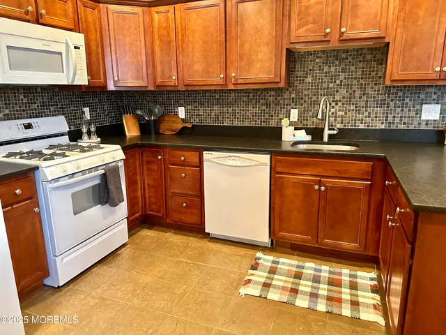 a kitchen with granite countertop a sink stove and cabinets