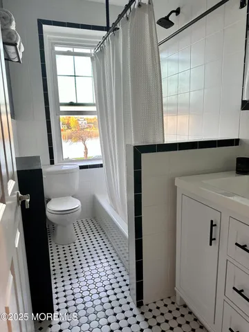 a bathroom with a sink a toilet a window and shower