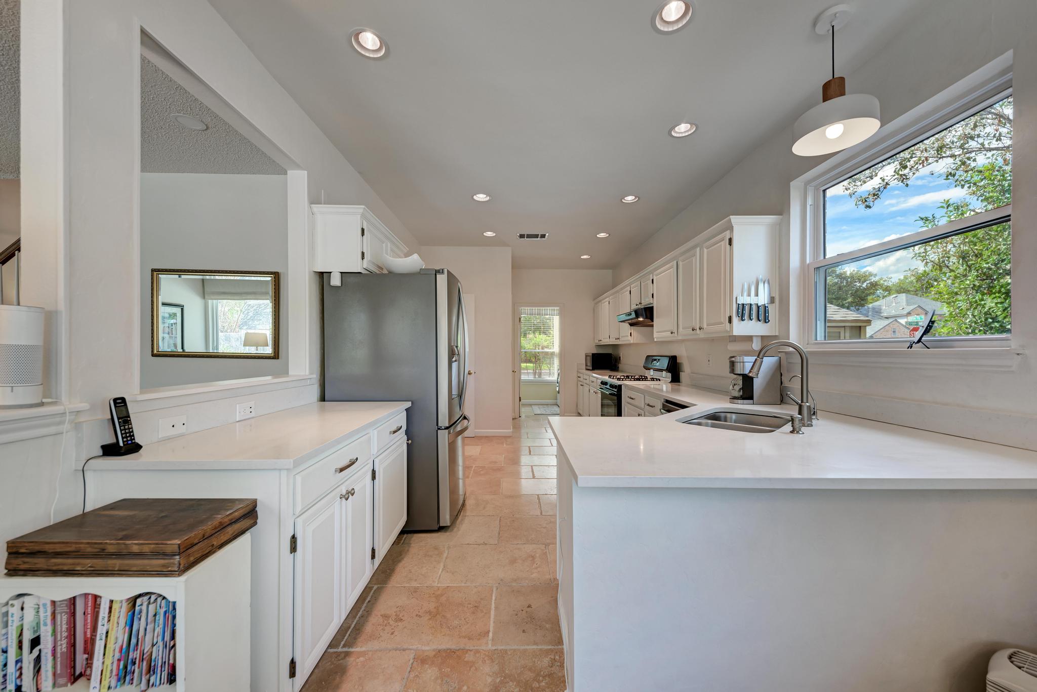 404 Cripple Creek Road Cedar Park, TX 78613 - Photo 16 of 39 Kitchen with white cabinetry, recessed lighting, stainless steel refrigerator with ice dispenser, range with gas stovetop, and hanging light fixtures