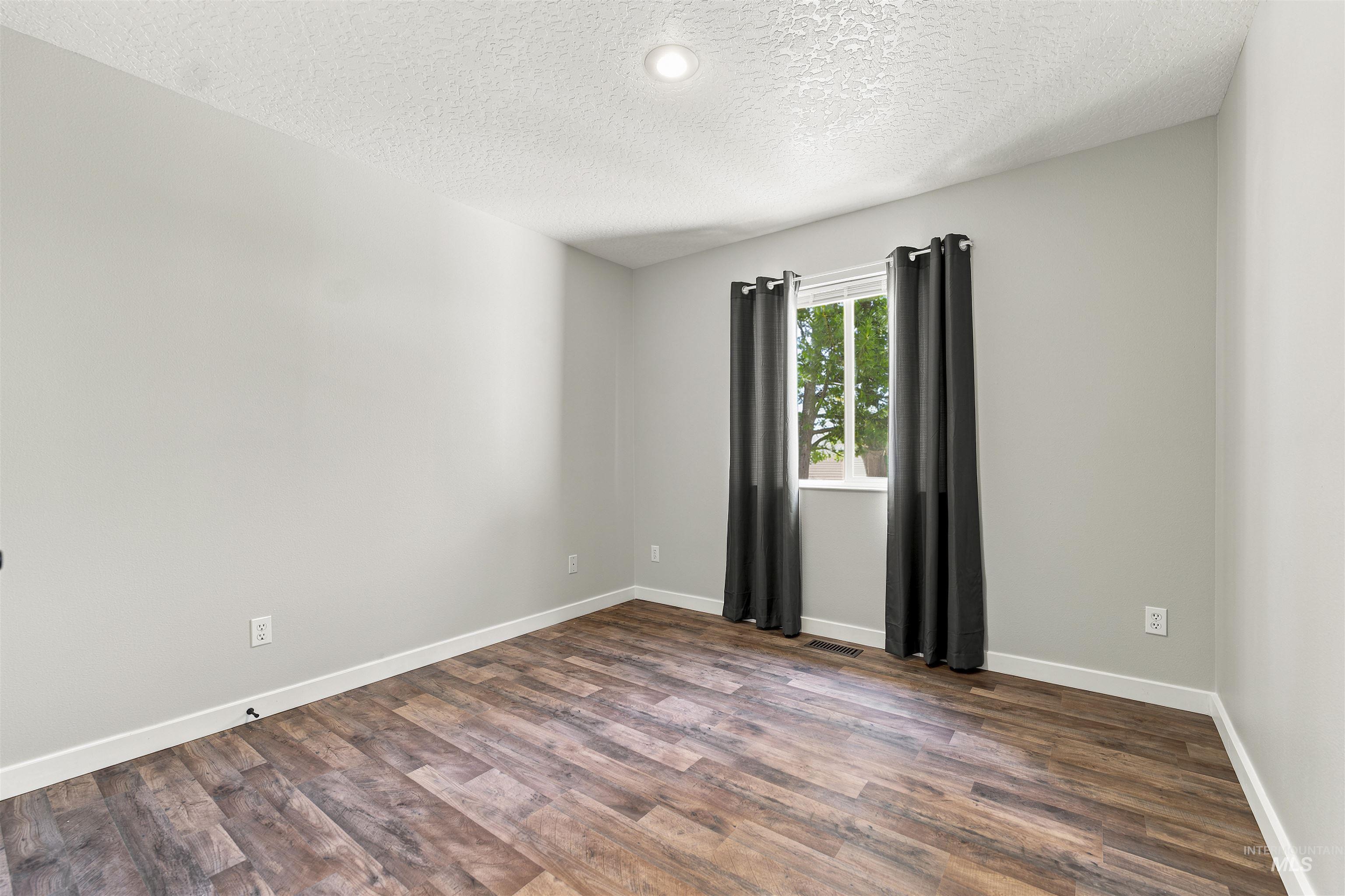 24864 Coventry Drive Caldwell, ID 83607 - Photo 23 of 49 Room featuring wood-finish flooring, a window with window blinds, and light gray painted walls