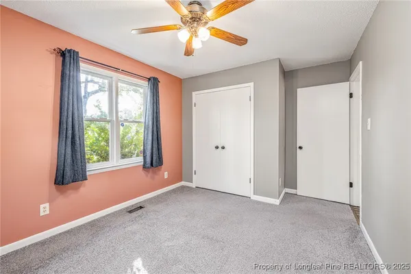 an empty room with windows and fan