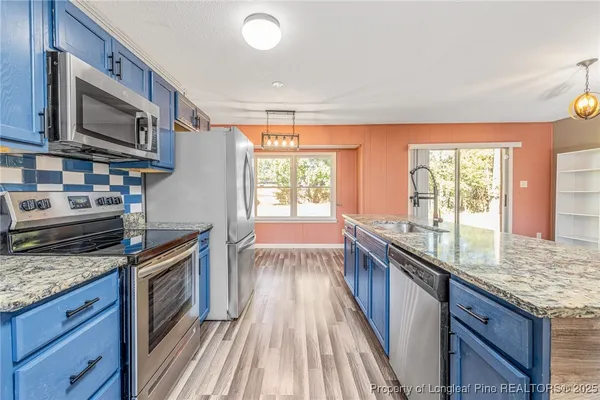 a kitchen with stainless steel appliances granite countertop a stove a sink and a microwave