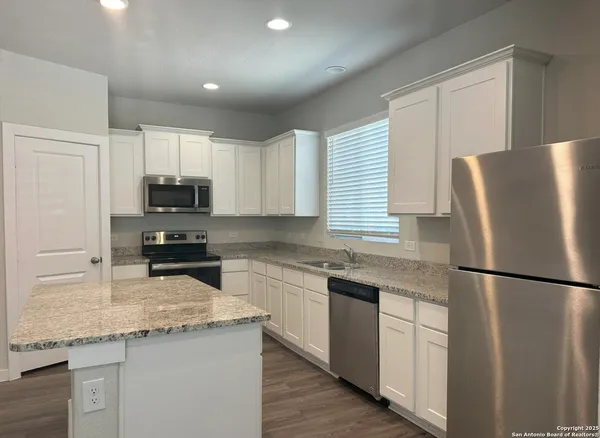 a kitchen with stainless steel appliances granite countertop a refrigerator sink stove microwave and cabinets