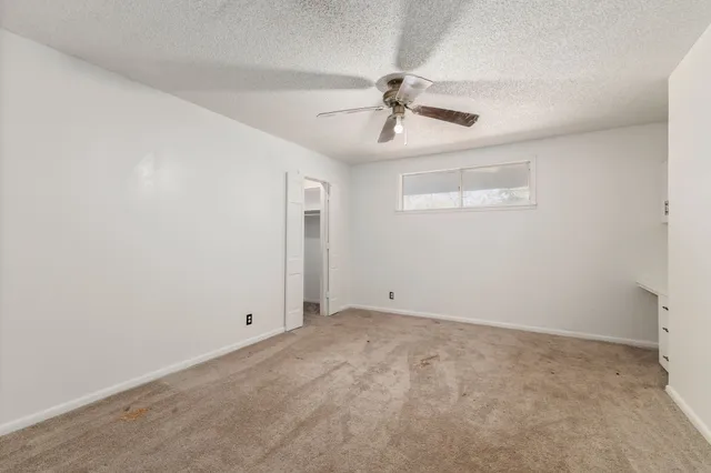an empty room with windows and fan