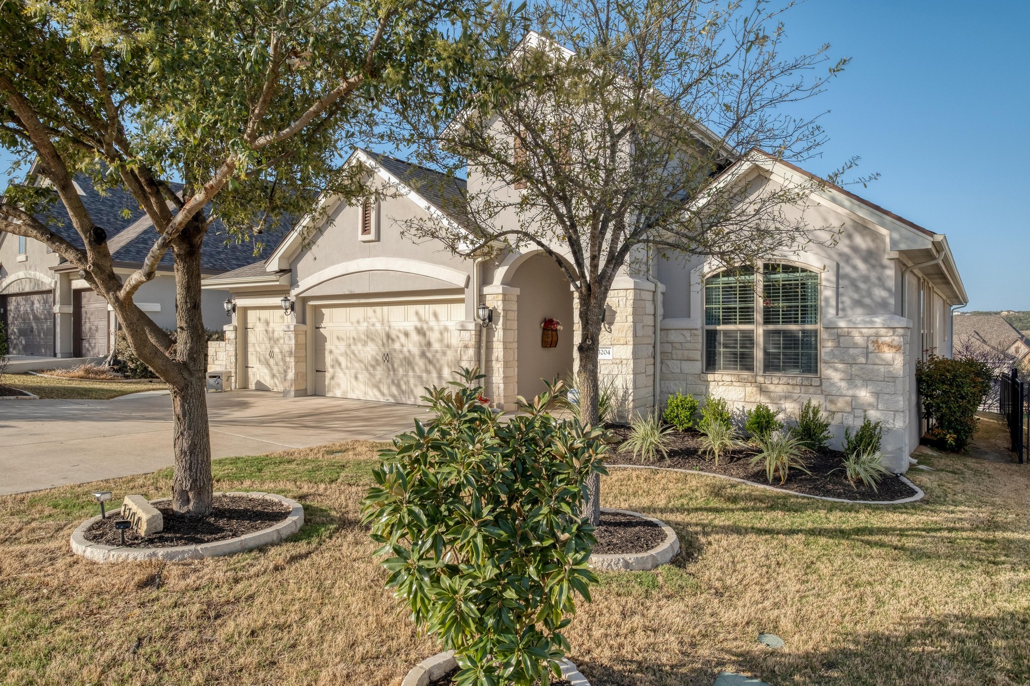 3204 Venezia View Leander, TX 78641 - Photo 23 of 28 View of front of property with stucco and stone siding, trees, and landscaped front yard