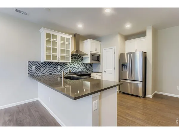 a kitchen with stainless steel appliances granite countertop a sink a refrigerator and wooden cabinets