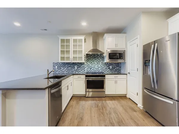a kitchen with granite countertop white cabinets and stainless steel appliances