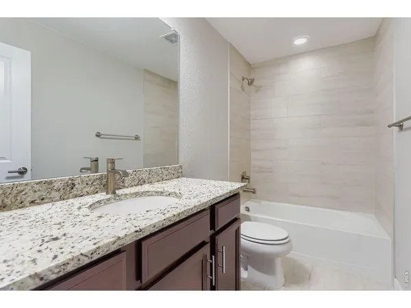 a bathroom with a granite countertop sink a toilet and shower