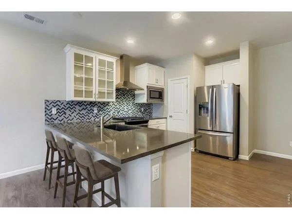 a kitchen with stainless steel appliances granite countertop a kitchen island hardwood floor and a refrigerator