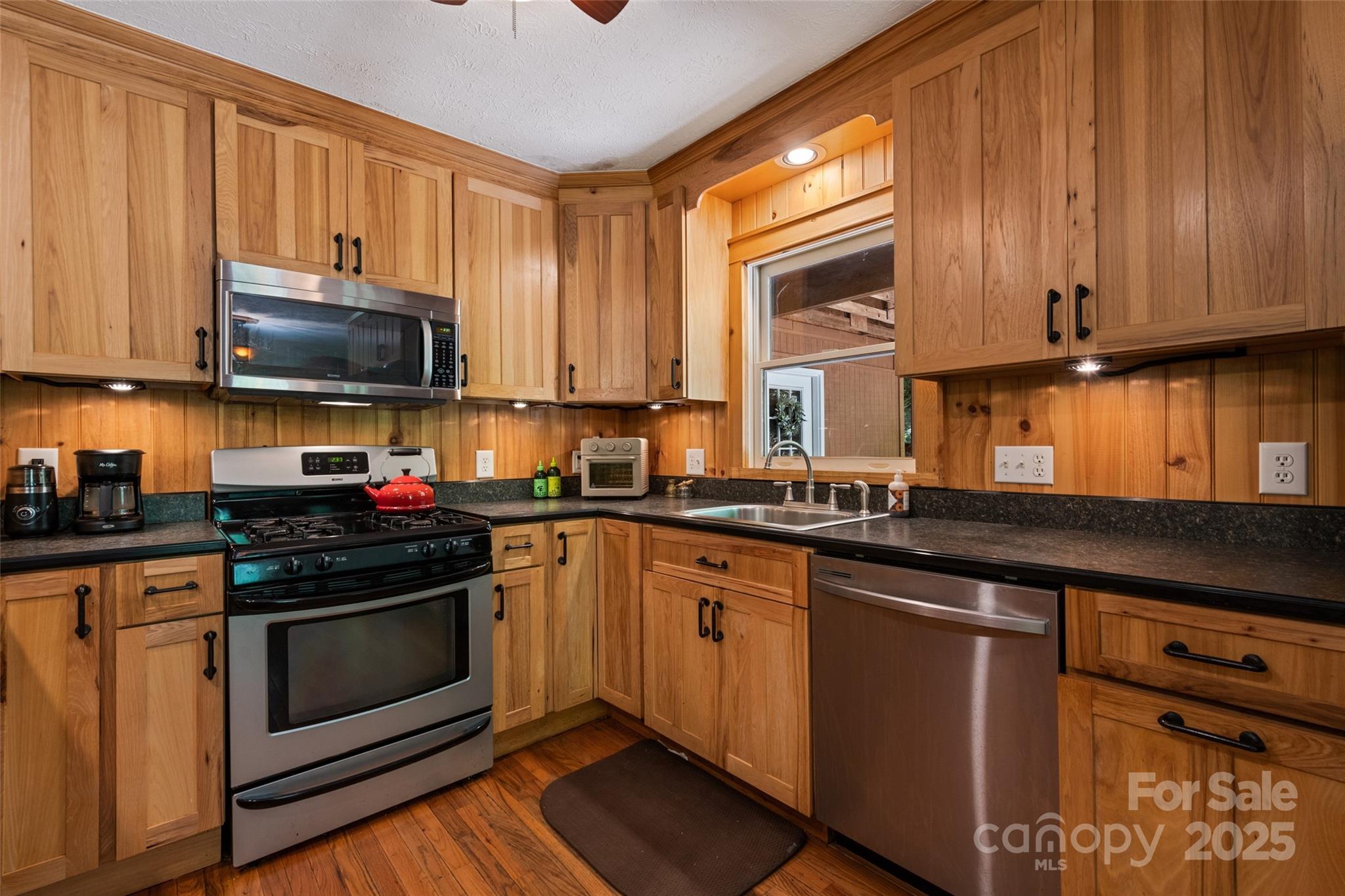 823 Turtle Creek Road Sylva, NC 28779 - Photo 16 of 38 a kitchen with granite countertop wooden cabinets stainless steel appliances and a window