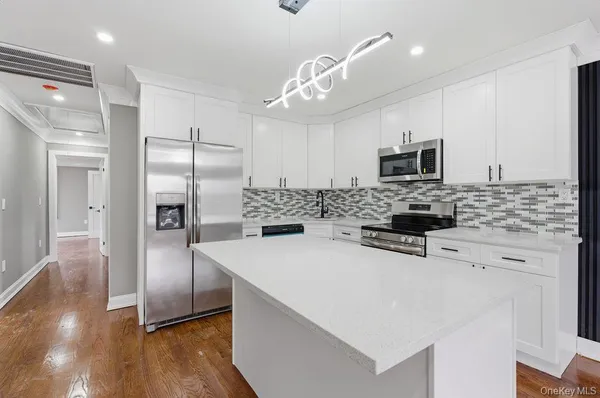 a kitchen with a refrigerator a sink cabinets and wooden floor