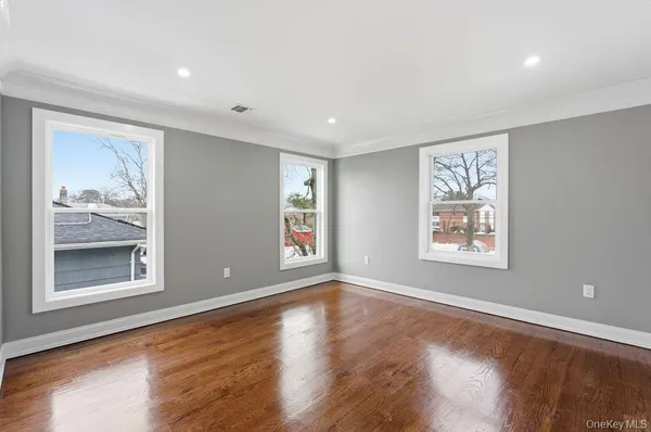 a view of an empty room with a window and wooden floor