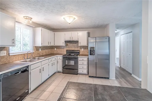 a kitchen with stainless steel appliances granite countertop a refrigerator and a sink